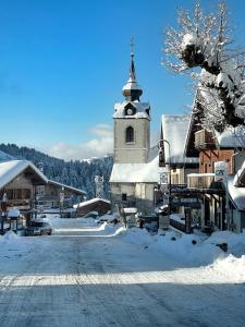 un village enneigé avec une église avec une cloche dans l'établissement Chez Francine, à Notre-Dame-de-Bellecombe