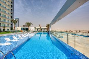 a swimming pool with lounge chairs on a building at Vibrant 1BR in Bella Rose Al Barsha South by Deluxe Holiday Homes in Dubai