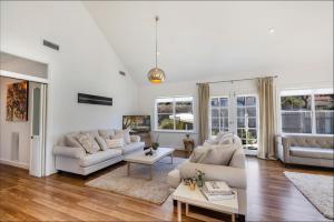 una sala de estar con muebles blancos y ventanas grandes. en Cumberland House, en Katoomba