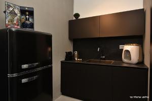 een zwarte keuken met een wastafel en een koelkast bij Y HOUSE SUITES in Mishmār Hāyardin