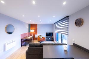 a living room with a couch and a clock on a wall at Luxurious Apartments Hackney near Train Station in London