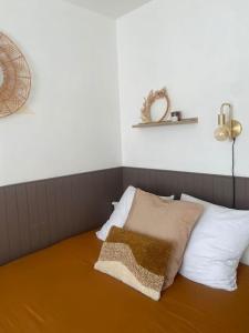 a bed with white pillows and a brown blanket on it at Studio avec Balcon proche Gare in Bourg-en-Bresse