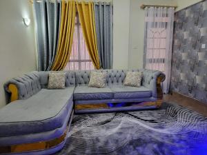 a living room with a blue couch and windows at Cozy Apartment in Ruaka