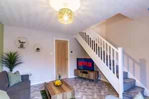 a living room with a tv and a staircase at K Suites - Goldcrest Road in Nottingham