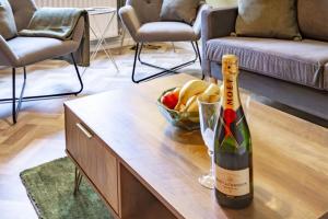 a bottle of wine and a bowl of fruit on a coffee table at K Suites - Goldcrest Road in Nottingham
