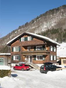 un bâtiment avec deux voitures garées dans un parking dans l'établissement Ferienhaus Schindeler, à Mellau