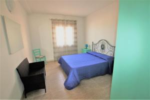- une chambre avec un lit bleu et une chaise dans l'établissement SHR Badesi, à Badesi