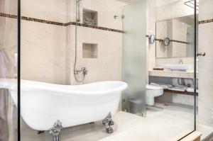 a white bathroom with a tub and a sink at Danai Hotel & Spa in Olympic Beach