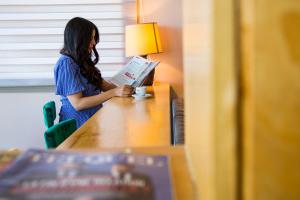 Valley Boutique Hotel في صافي: امرأة تجلس على طاولة تقرأ كتابا