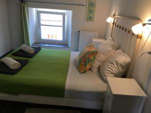 a bedroom with a bed with a green comforter and a window at Hotel Axat in Axat