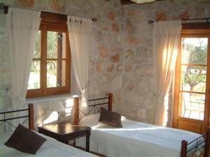 a bedroom with two beds and a stone wall at Villa Karissa - Zante in Vasilikos