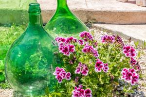 two green glass bottles sitting next to some flowers at Il mondo dei sogni in Porto Cesareo