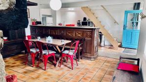 a dining room with a table and red chairs at Le penty de Lesquiffinec in Crozon