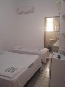 a hotel room with two beds and a window at Hotel Algaroba in Bom Jesus da Lapa