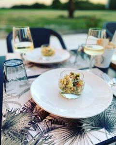 un tavolo con una ciotola di cibo e bicchieri di vino di Château de Neyran chambre d'hôtes & Spa a Soulac-sur-Mer