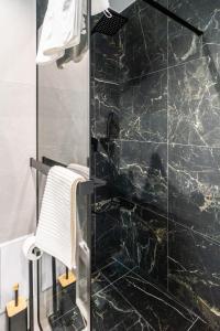 a bathroom with a shower with a black marble wall at Apartament Górska Polana by Apart Concept Podhale in Kościelisko