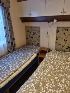 two beds in a small room with a window at Chalet Zanderij nr. 16 op Chaletpark Bregkoog in De Koog