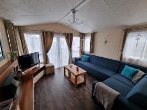 ein Wohnzimmer mit einem blauen Sofa und einem TV in der Unterkunft Chalet Zanderij nr. 16 op Chaletpark Bregkoog in De Koog