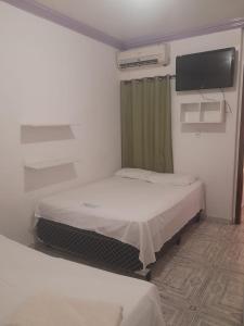 a room with two beds and a flat screen tv at Pousada Algaroba in Bom Jesus da Lapa