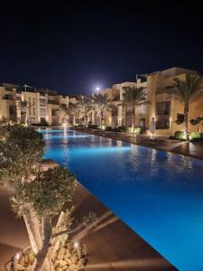 una gran piscina por la noche con luces azules en Mangroovy - 1BR GF +2 wall beds Garden & Pool view, en Hurghada