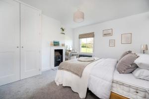 a white bedroom with a bed and a fireplace at 3 Lower Falkland Cottage Long Melford in Sudbury
