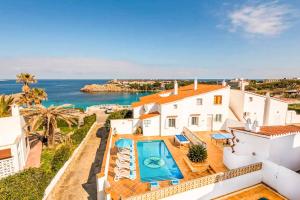 Una casa blanca con piscina y el océano. en Vista Arenal, en Arenal d'en Castell