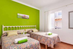 Un dormitorio con dos camas y una pared verde. en Vista Arenal, en Arenal d'en Castell 9 fotos más