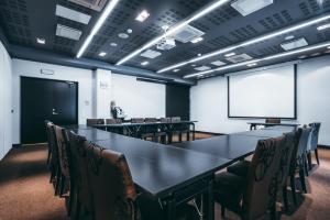 a conference room with a table and chairs and a screen at Arensburg Boutique Hotel & Spa in Kuressaare