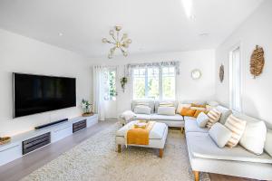 sala de estar con muebles blancos y TV de pantalla plana en Villa Björkbacken, en Nummela
