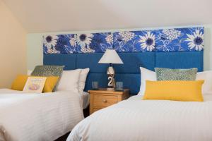 a bedroom with two beds and a blue headboard at Harlyn lodge Hot Tub Lodge at Retallack Resort in Saint Columb Major