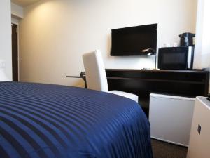 a hotel room with a bed and a desk with a tv at HOTEL LiVEMAX Osaka Umeda Nakatsu in Osaka