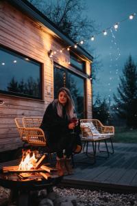 a woman sitting on a deck next to a fire at Coniferis in Tomnatic
