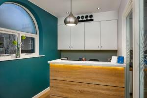 a kitchen with white cabinets and a blue wall at Seraphine Hammersmith Hotel in London