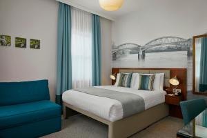 um quarto com uma cama e uma cadeira azul em Seraphine Hammersmith Hotel em Londres