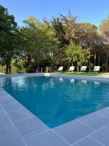 une piscine bleue avec 2 chaises et des arbres dans l'établissement Can Jan Vives, à Vidreres