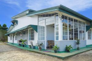 a white house with large windows and plants at Gregory House Hostel in Nuwara Eliya