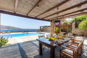 un patio con una mesa y una piscina en Villa Myrto, breathtaking Aegean view, 5' from Koundouros beach, en Koundouros