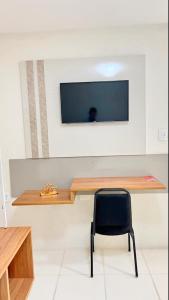 a desk with a chair and a television on a wall at Avelan Plaza Hotel in Nossa Senhora da Glória