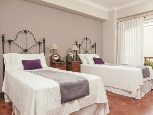two beds in a bedroom with white and purple at Solar De La Plaza in Salta +22 photos