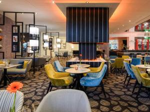 a restaurant with tables and chairs and a bar at Mercure Hotel Bochum City in Bochum
