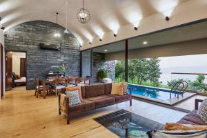 sala de estar de planta abierta con sofá y mesa en SaffronStays Yahvi Waters by Kosha Villas, Pawna - pool villa with stunning lake view, en Lonavala