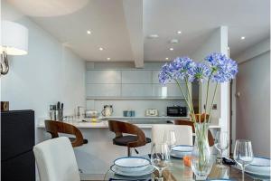 eine Küche mit einem Tisch und einer Vase mit lila Blumen in der Unterkunft Deganwy Tower Apartment in Deganwy