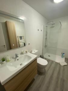 een badkamer met een wastafel, een toilet en een spiegel bij Céntrico, amplio y bonito apartamento en Cambados in Cambados