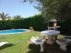 een tuin met een tafel en stoelen naast een zwembad bij Villa Lunas in Cala'n Bosch