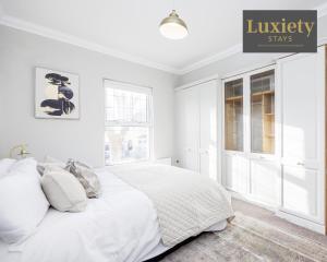 biała sypialnia z łóżkiem i znakiem, który czyta luksusowe pobyty w obiekcie Modern house - City Centre - Contractors Hub, Families, Free Parking by Luxiety Stays w Southend-on-Sea