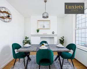 a dining room with a table and green chairs at Modern house - City Centre - Contractors Hub, Families, Free Parking by Luxiety Stays in Southend-on-Sea