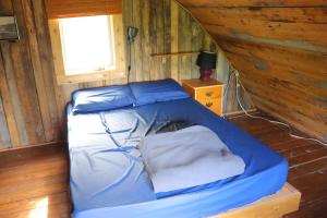 a bed in a wooden room with a window at Auberge/Chalet Griffon Aventure in L’Anse-au-Griffon