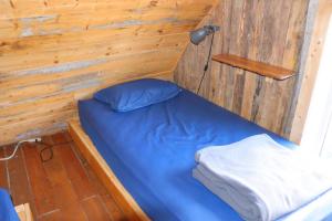 a small bedroom with a blue bed in a wooden wall at Auberge/Chalet Griffon Aventure in L’Anse-au-Griffon