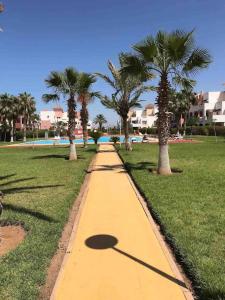 a yellow path in a park with palm trees at LA BELLA VIDA in Saïdia