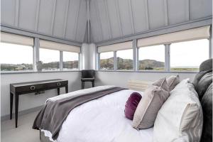 a bedroom with a bed and a desk and windows at Deganwy Tower Apartment in Deganwy